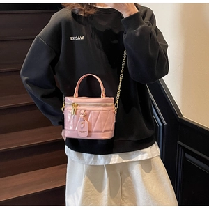 Detail der rosa Zylindertasche mit V-Steppmuster und goldener Ketten-Schulterriemen