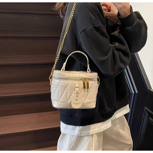 Detail einer weißen gesteppten Beuteltasche mit goldener Kette auf einer Vintage-Treppe