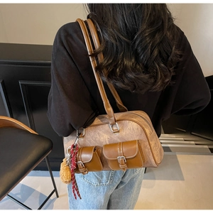 Detail view of vintage brown leather tote bag with pocket features and plush charm
