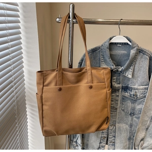 Detail of canvas tote bag with functional button pockets and side water bottle holder