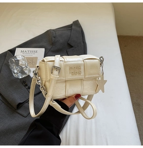 Détail du sac bandoulière tissé crème avec gaufrage de lettres et pendentif étoile