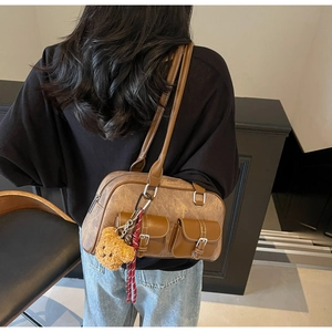Brown vintage Boston bag with buckle pockets and teddy bear charm on model shoulder