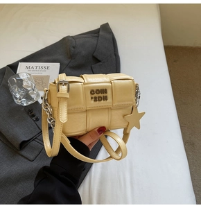 Détail du sac à bandoulière tissé jaune avec lettres en métal et pendentif étoile