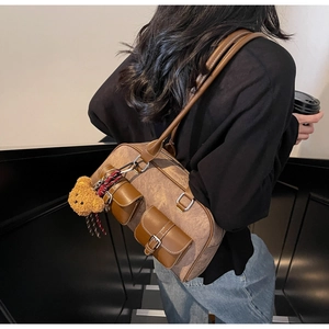 Detailed shot of retro brown tote bag with twin pockets and a cute bear charm pendant