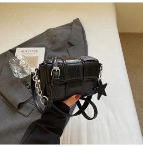Détail d'un sac bandoulière tissé noir avec chaîne argentée et pendentif étoile