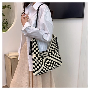Detail of checkered crochet shoulder bag with black tassels and woven strap on model