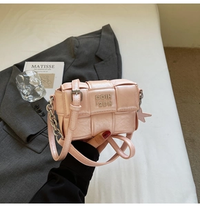 Détail du sac bandoulière tissé rose avec logo métallique et breloque étoile