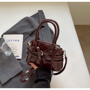 Close-up of glossy wine red shell bag with silver hardware and detachable shoulder strap
