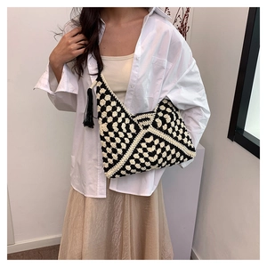 Detail of checkered knit shoulder bag featuring black tassels and handmade woven texture
