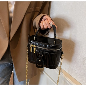 Detailansicht der schwarzen Lackleder-Eimertasche mit Goldreißverschluss und Kettenriemen
