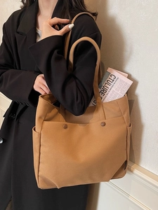 Brown canvas tote bag with side pockets and button details shown on model