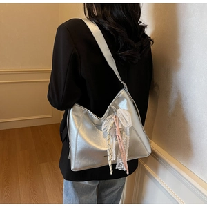 Detail of silver metallic hobo bag with lace charm accessory on a female model