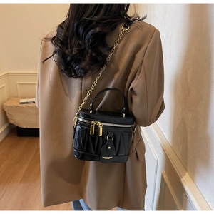Detail der schwarzen Bucket Bag mit Plissee-Design, Goldkette und Lederanhänger