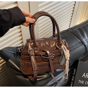 Detail of dark brown patent leather handbag with decorative knot and woven rope charm