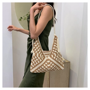 Detail of crochet shoulder bag with geometric pattern and tassels on model