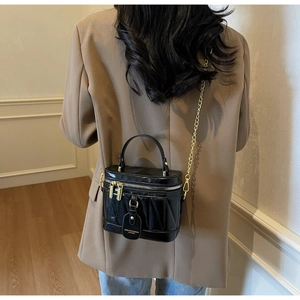 Makroaufnahme der schwarzen Lackleder-Beuteltasche mit Ziernähten und goldener Kette