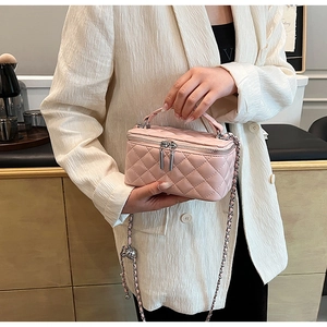 Detail shot of a pink quilted mini bag with silver chain strap and metal ball charm