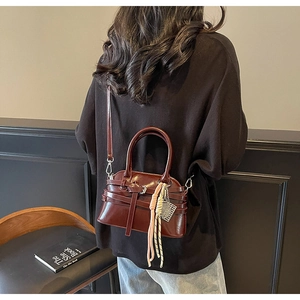 Detail of dark burgundy faux leather bag with knot pendant shown in a retro lifestyle setting