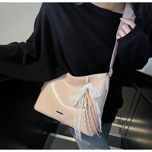 Detail of pink faux leather bag featuring lace bow charm and silver metal accents