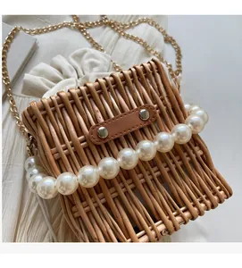 Detail of woven straw bucket bag with pearl handle and drawstring inner lining