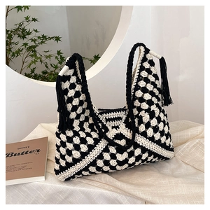Detail of hand-woven black and white checkerboard tote bag with stylish black tassels