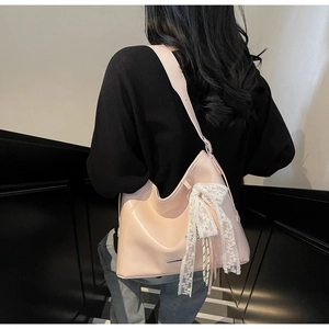 Rear view of a model wearing the light pink hobo bucket bag with white lace bow detail