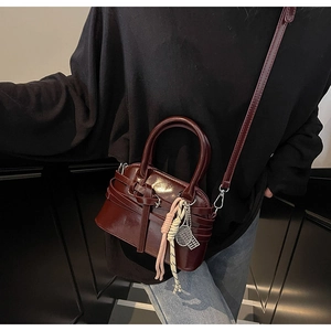 Detail of burgundy leather shell bag featuring woven cord and metal racquet charm