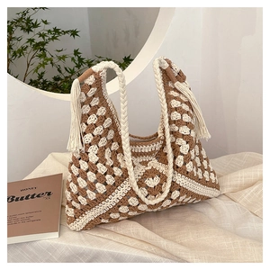 Close-up of bohemian woven armpit bag with tassels on a stylish aesthetic background