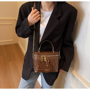 Detail der dunkelbraunen Vintage Eimertasche mit Goldreißverschlüssen und Kette