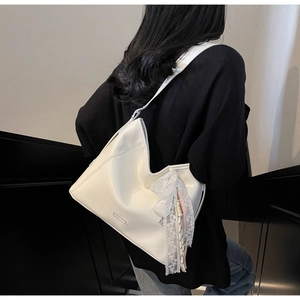 Detail of off-white large hobo bag with lace and pearl charm on a wide shoulder strap