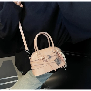 Detail of apricot pink shell bag with crisscross leather straps and metal buckle accents
