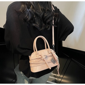 Detail of apricot pink shell bag with cross strap and decorative checkered silk scarf