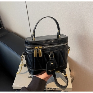 Detail einer schwarzen Stepp-Beuteltasche mit goldenem Reißverschluss und Anhänger