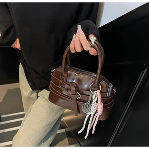 Close-up of brown patent leather shell bag with tennis racket and rainbow charms
