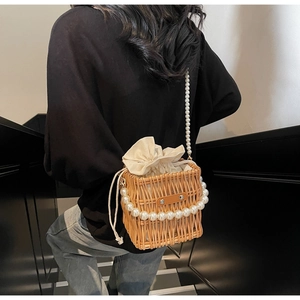 Detail of woven straw bucket bag with pearl chain handle and drawstring linen insert