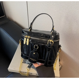 Detailaufnahme einer schwarzen Leder-Box-Tasche mit Steppmuster und goldener Kette