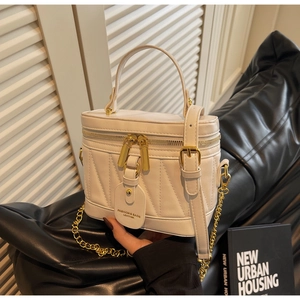 Detail der cremefarbenen Beuteltasche mit V-Steppung, Goldreißverschlüssen und Anhänger