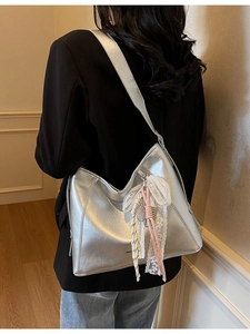 Minimalist silver metallic bucket bag with lace bow pendant and wide shoulder strap