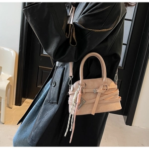Detailed view of pink leather shell bag with woven strap trim on a stylish model
