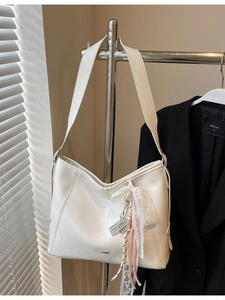 White large capacity hobo shoulder bag with lace scarf and tassel hanging on a metal rack