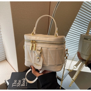 Detailansicht der beigen gesteppten Eimertasche mit Goldkette und Fashion-Anhänger