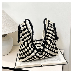 Detail of crochet weave texture and black tassels on a checkerboard shoulder bag