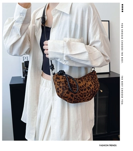 Detail view of leopard print crescent bag with black knotted zip and slim leather strap