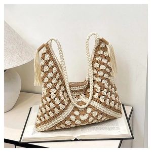 Close-up of bohemian crochet shoulder bag with floral patterns and tassel strap details