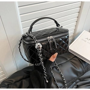 Detail of black quilted leather box bag featuring silver chain and adjustable metal ball