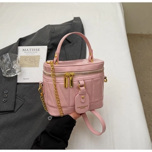 Detail der gesteppten Lederbeuteltasche in Rosa mit Goldreißverschlüssen und Kette