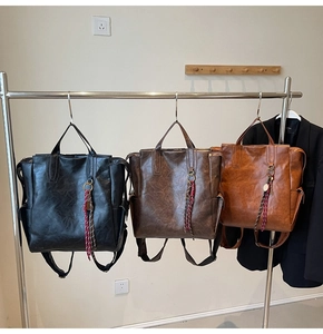 Three vintage leather backpacks in black and brown hanging to show large storage capacity