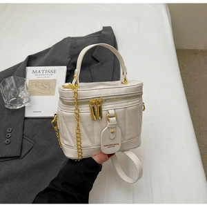 Detail der cremefarbenen Beuteltasche mit V-Steppung und goldener Kettenhalterung