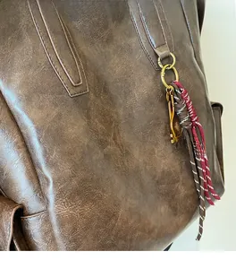 Detail of dark brown vintage faux leather backpack with woven cord and metal ring ornament