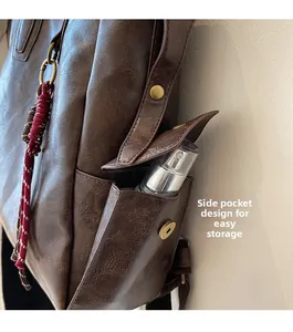 Detail view of the side pocket with magnetic buckle and decorative woven cord on the brown bag